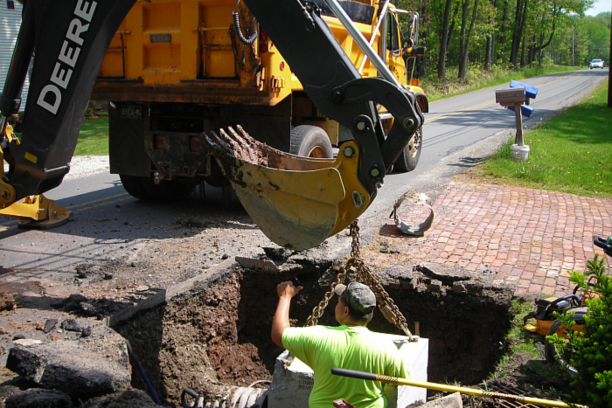 Catchbasin replacement on Griffin Road: man standing in hole  - roadwork apparatus next to hole at road level